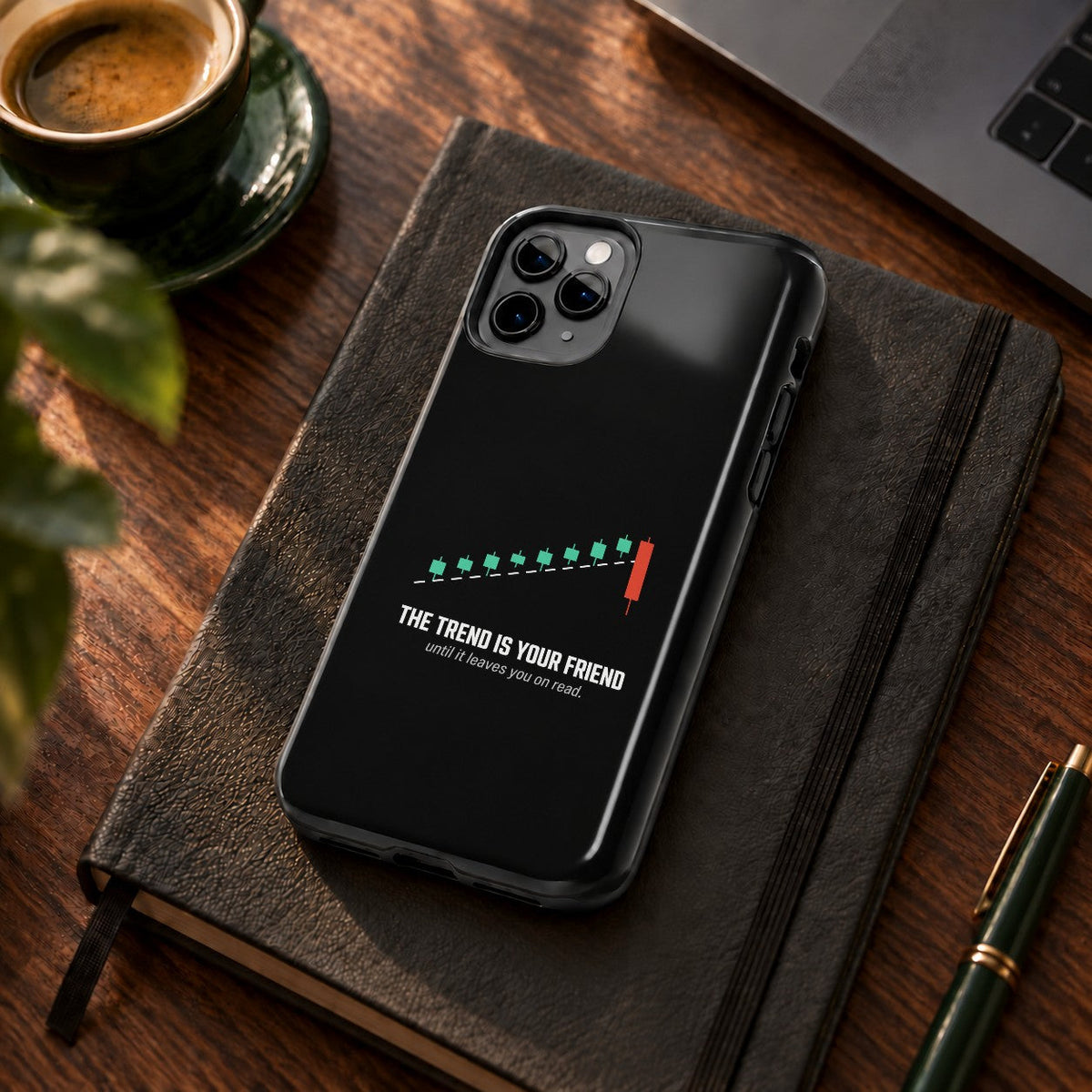 The Trend Is Your Friend phone case on a desk with coffee and a notebook